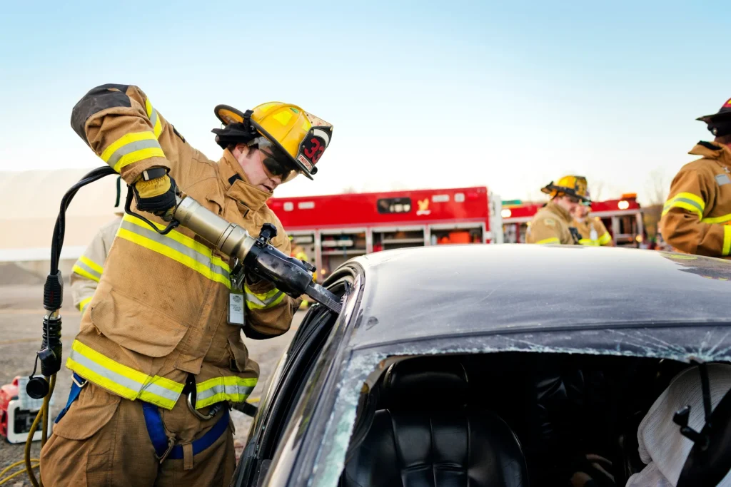 A firefighter cutting a victim out of a car after experiencing a devastating car accident injury.