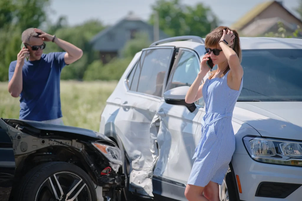 A woman and a man standing by their cars after a car accident and calling their Austin car accident lawyers.