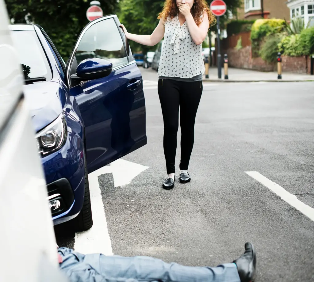 Woman standing by her car after hitting a pedestrian.