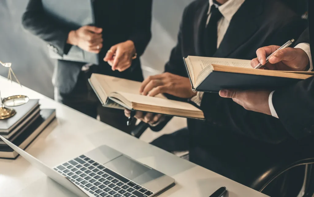 A group of attorneys looking at books and their computer.