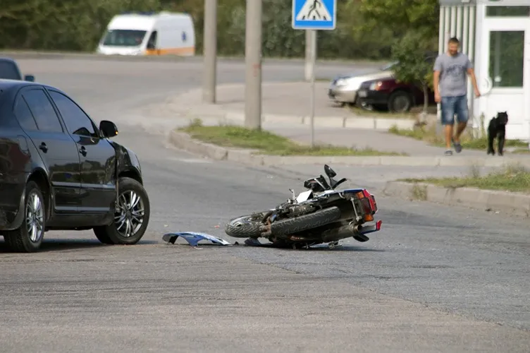 A motorcycle and car accident in the middle of the road.