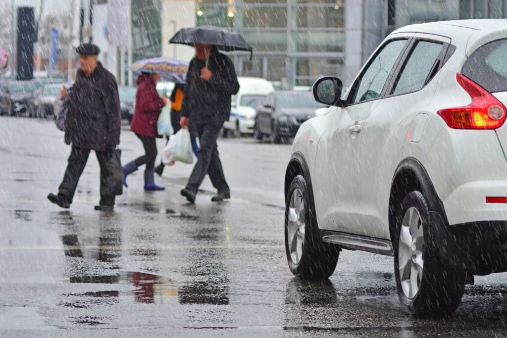 Pedestrians crossing a street in the rain.