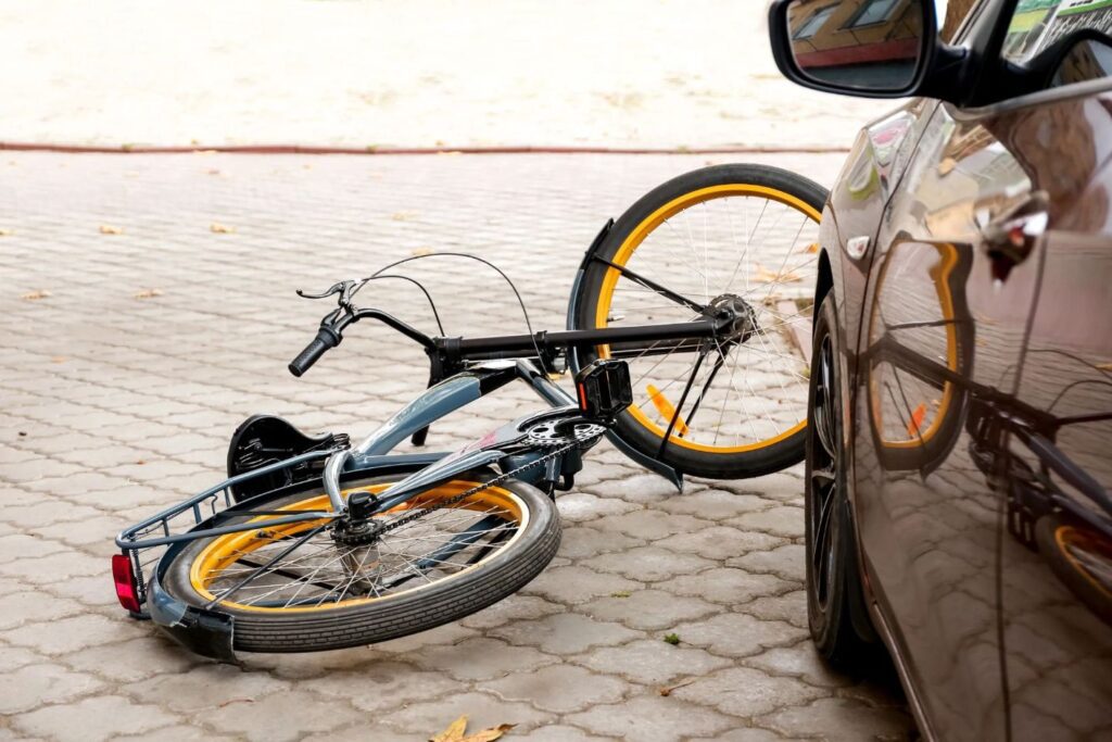 A bicycle on the ground in front of a car.